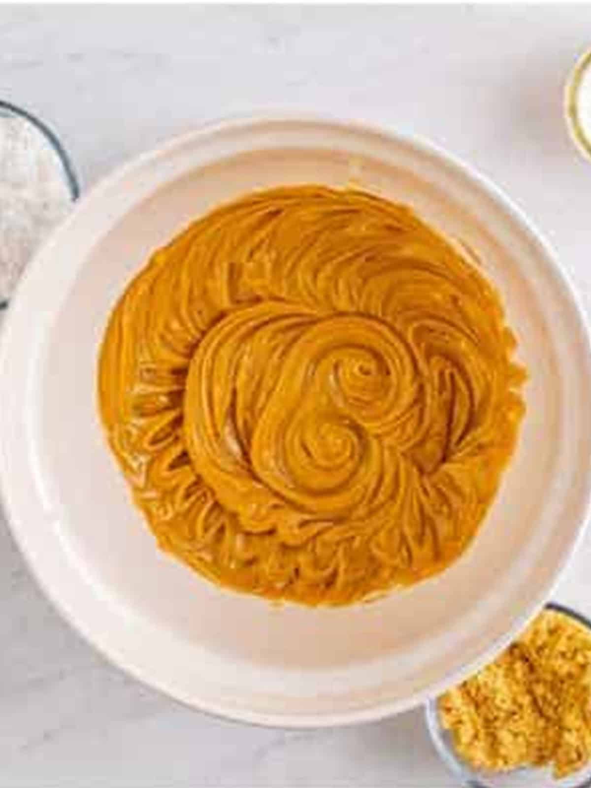 Creamy peanut butter and butter creamed together in a bowl for peanut butter cake.