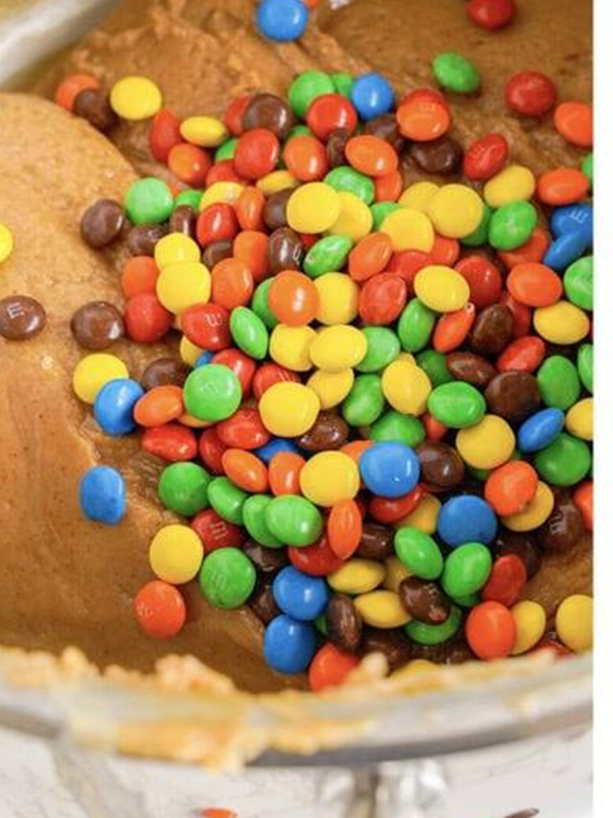Folding colorful M&Ms into the peanut butter fudge.