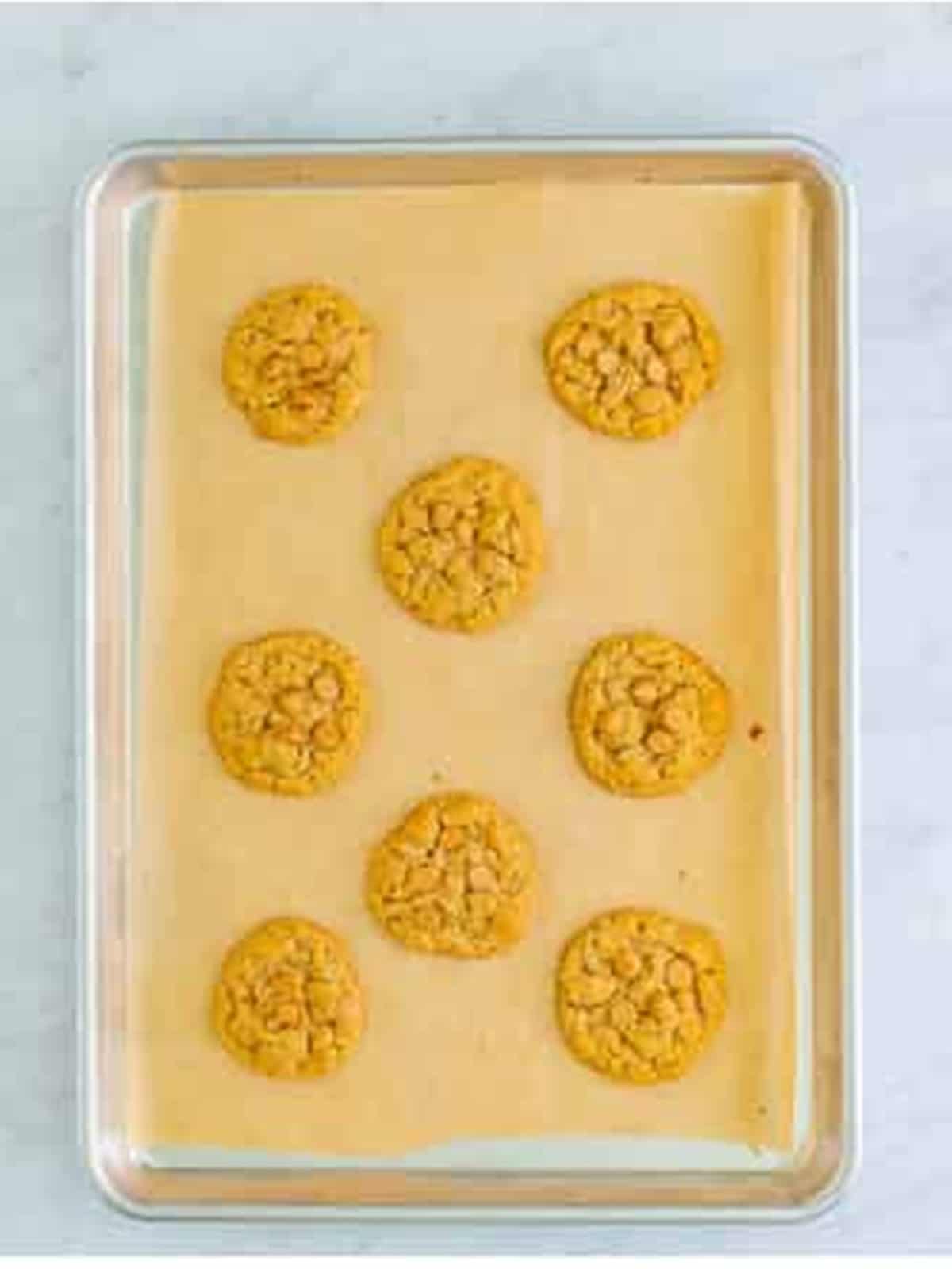 Baked peanut butter oatmeal cookies cooling on a parchment-lined sheet tray.