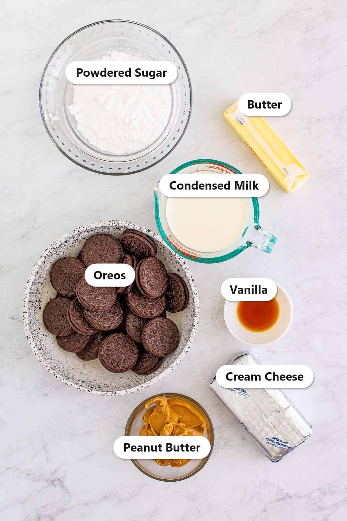 Labeled ingredients for no bake peanut butter pie including Oreos, butter, cream cheese, peanut butter, powdered sugar, sweetened condensed milk, and vanilla.