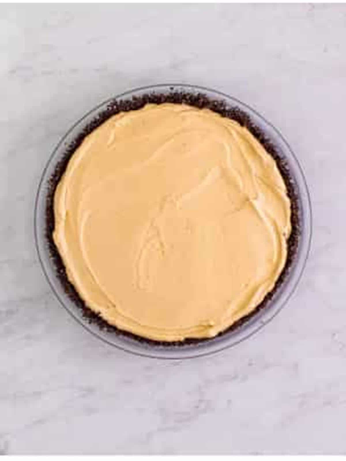 Smooth peanut butter filling spread into an Oreo crust ready to chill.