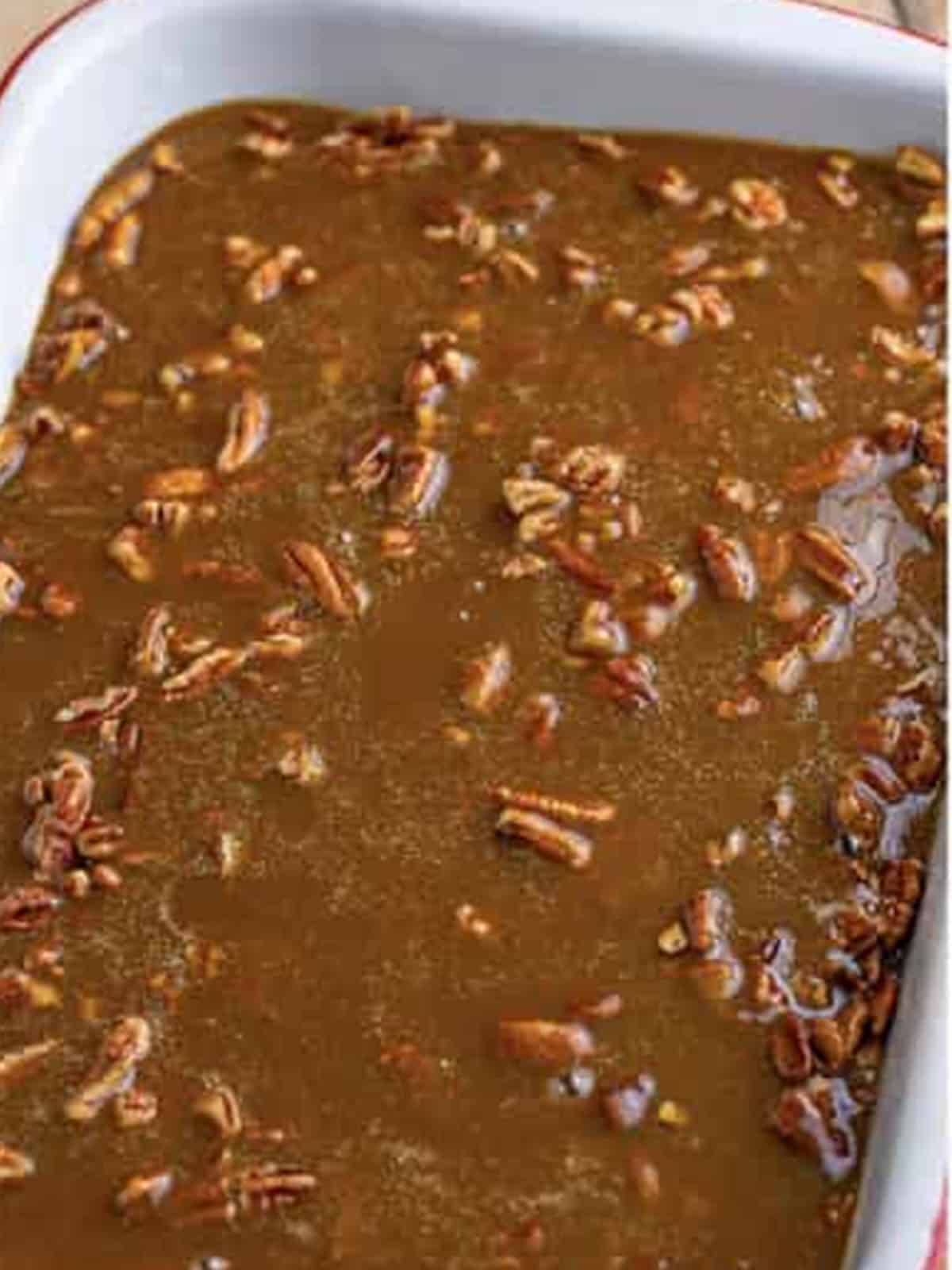 Pecan cobbler filling poured over pecans in a baking dish.