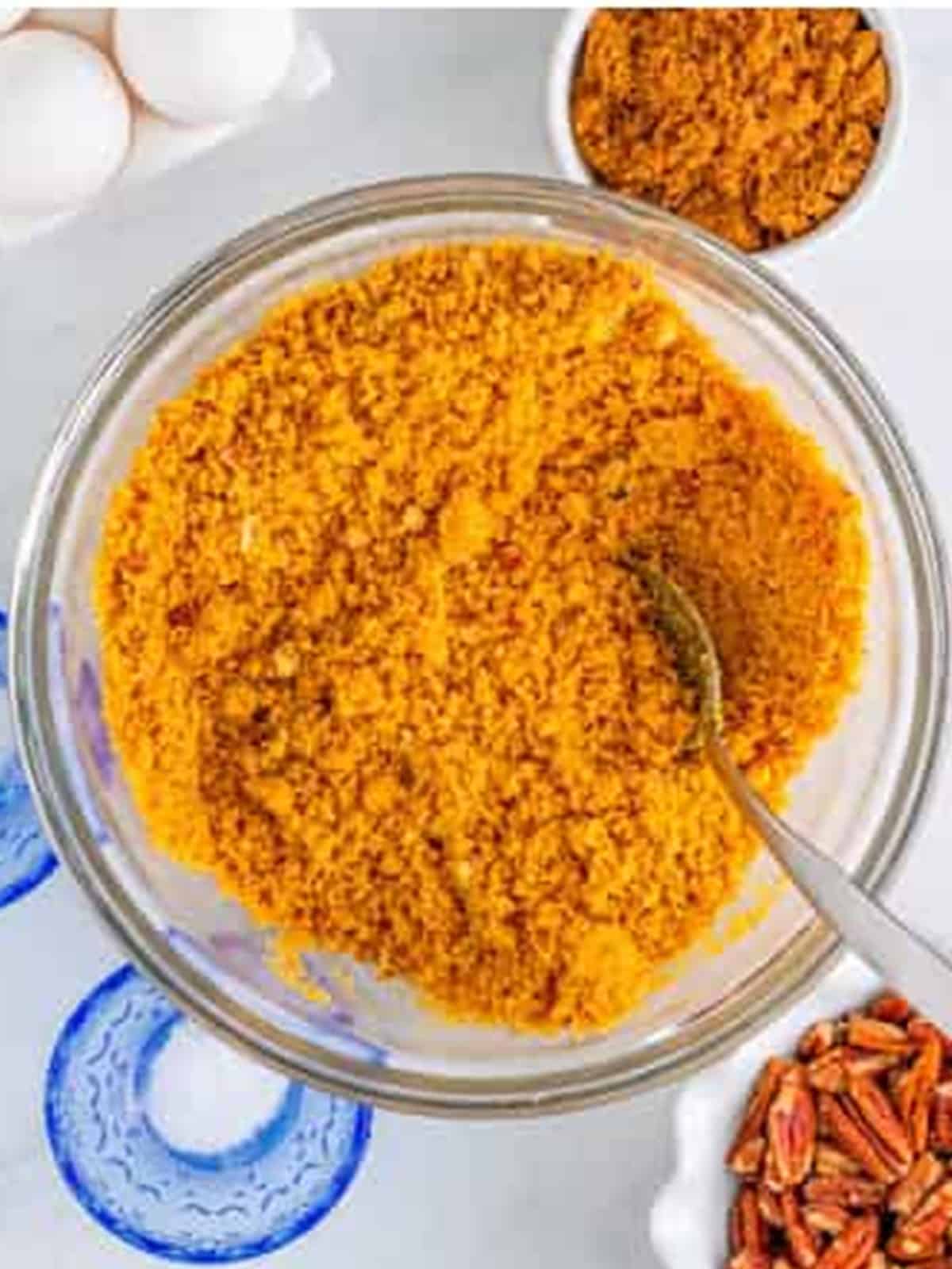Graham cracker crumbs, pecans, sugar, and butter mixed for the pecan pie cheesecake crust.