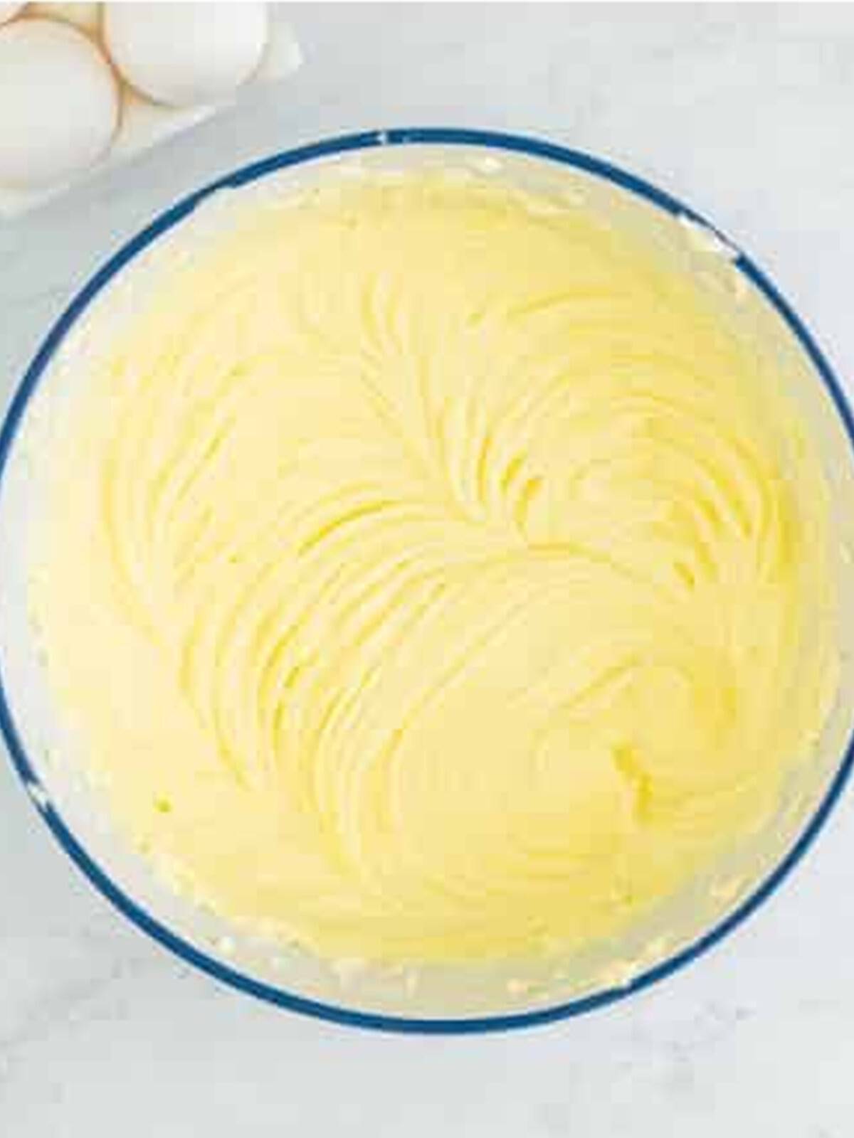 Cream cheese whipped smooth in a bowl for pecan pie cheesecake filling.