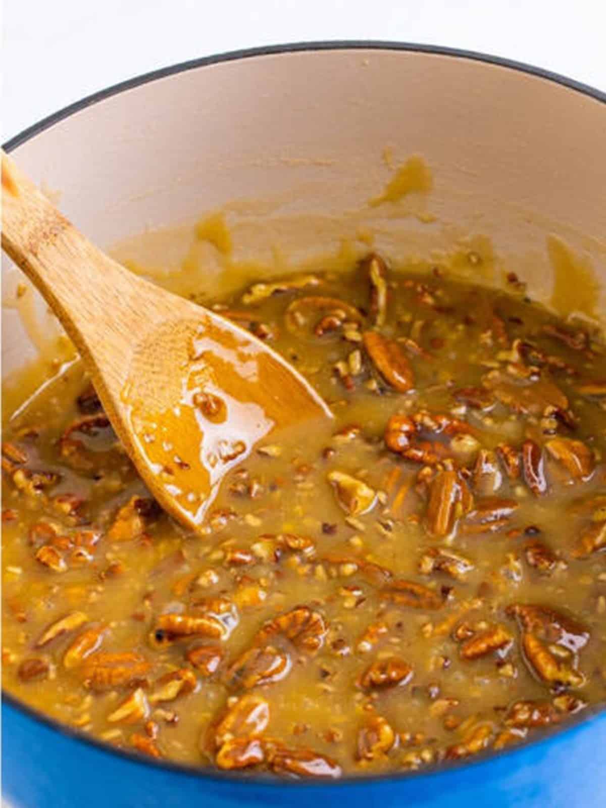 Pecan halves and chopped pecans stirred into the cooked praline candy with a wooden spoon.