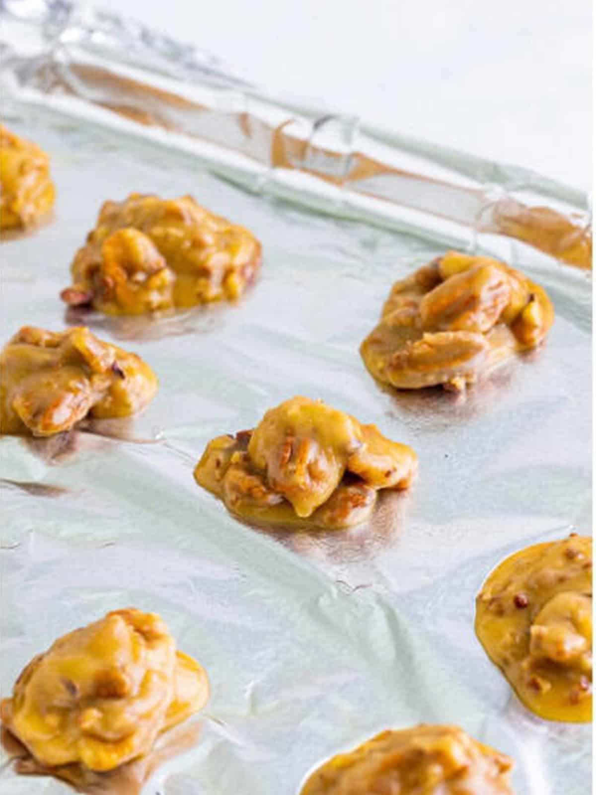 Spoonfuls of pecan pralines dolloped onto a foil lined tray to harden.