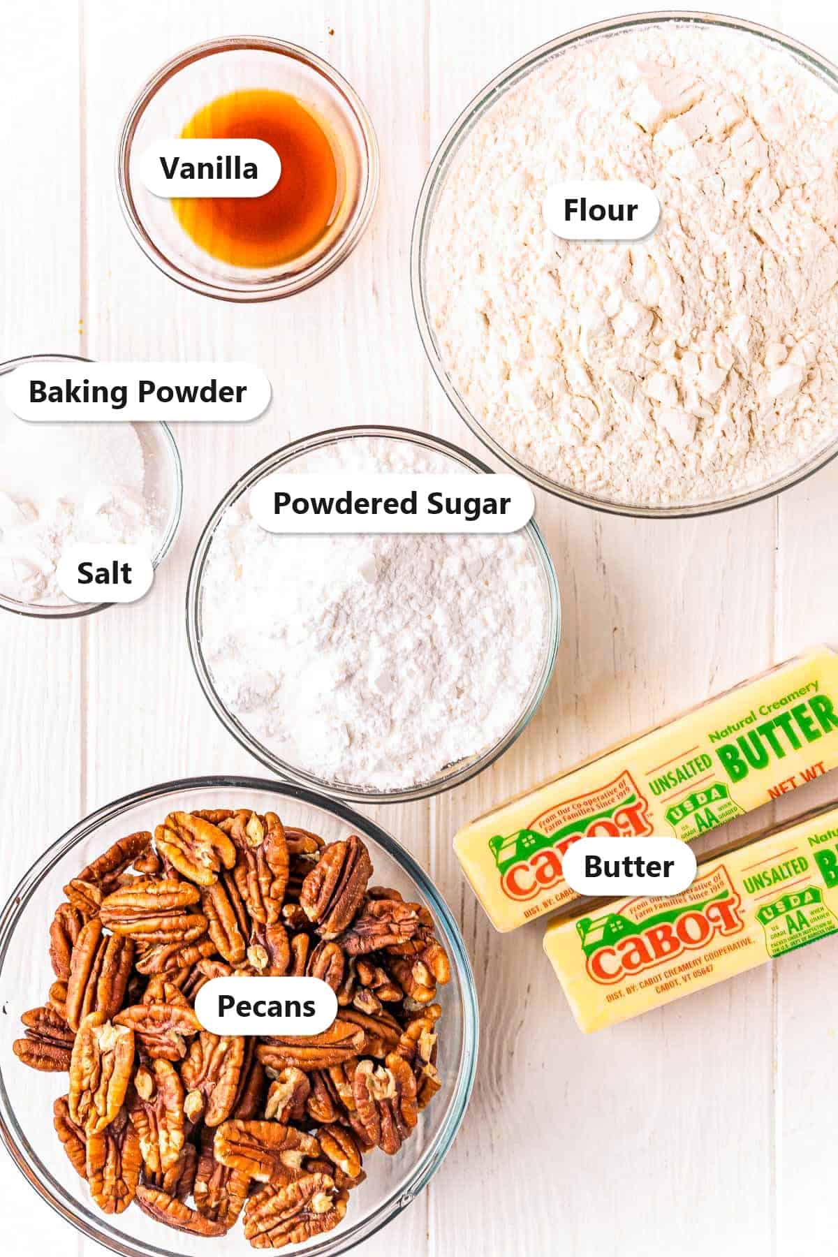 Labeled ingredients for pecan sandies including pecans, flour, butter, powdered sugar, vanilla, baking powder, and salt.