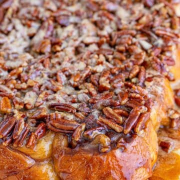 A pan of from scratch pecan sticky buns glazed with caramel and toasted pecans.