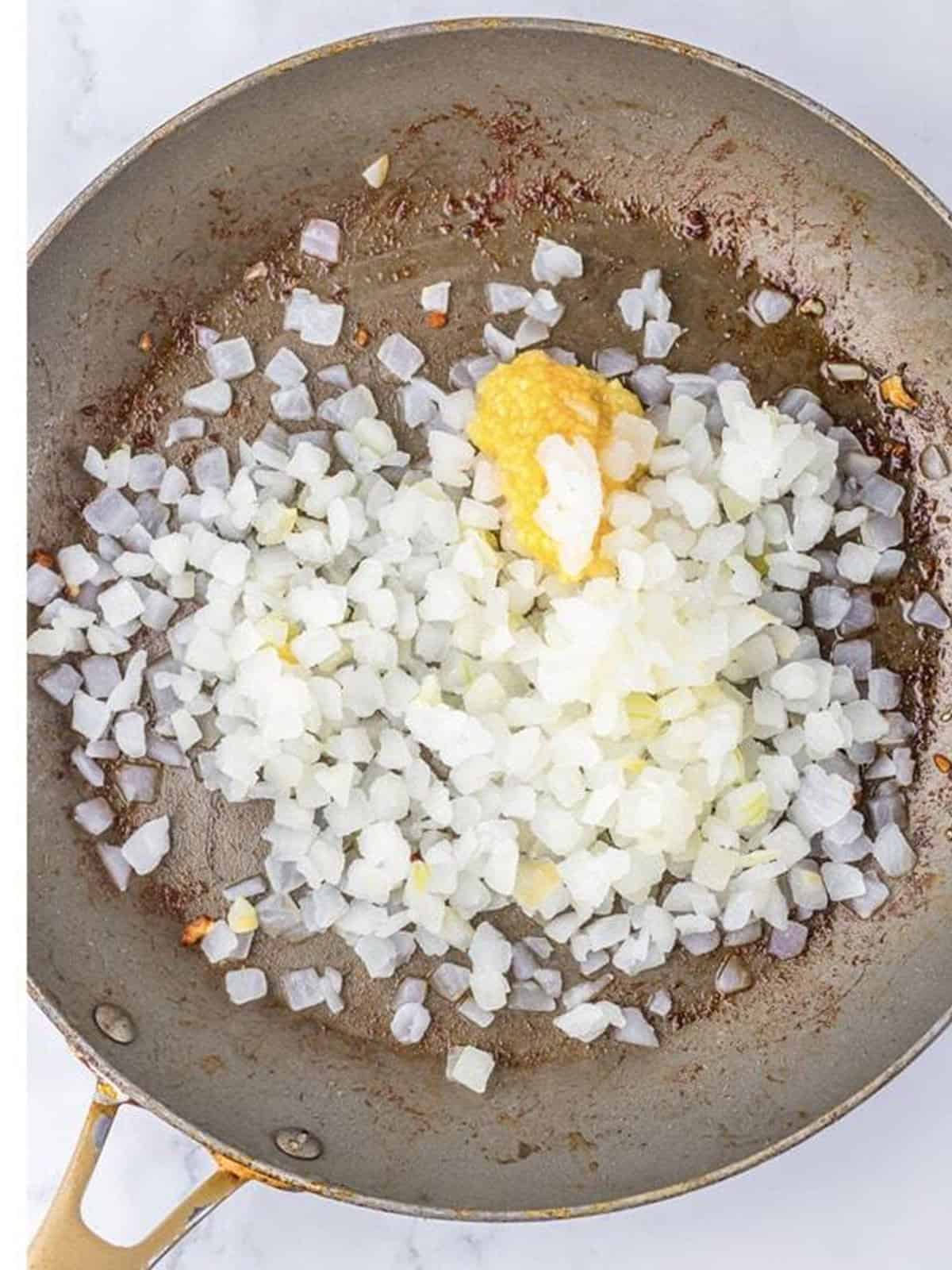 Diced onion and minced garlic sauteing in a skillet.
