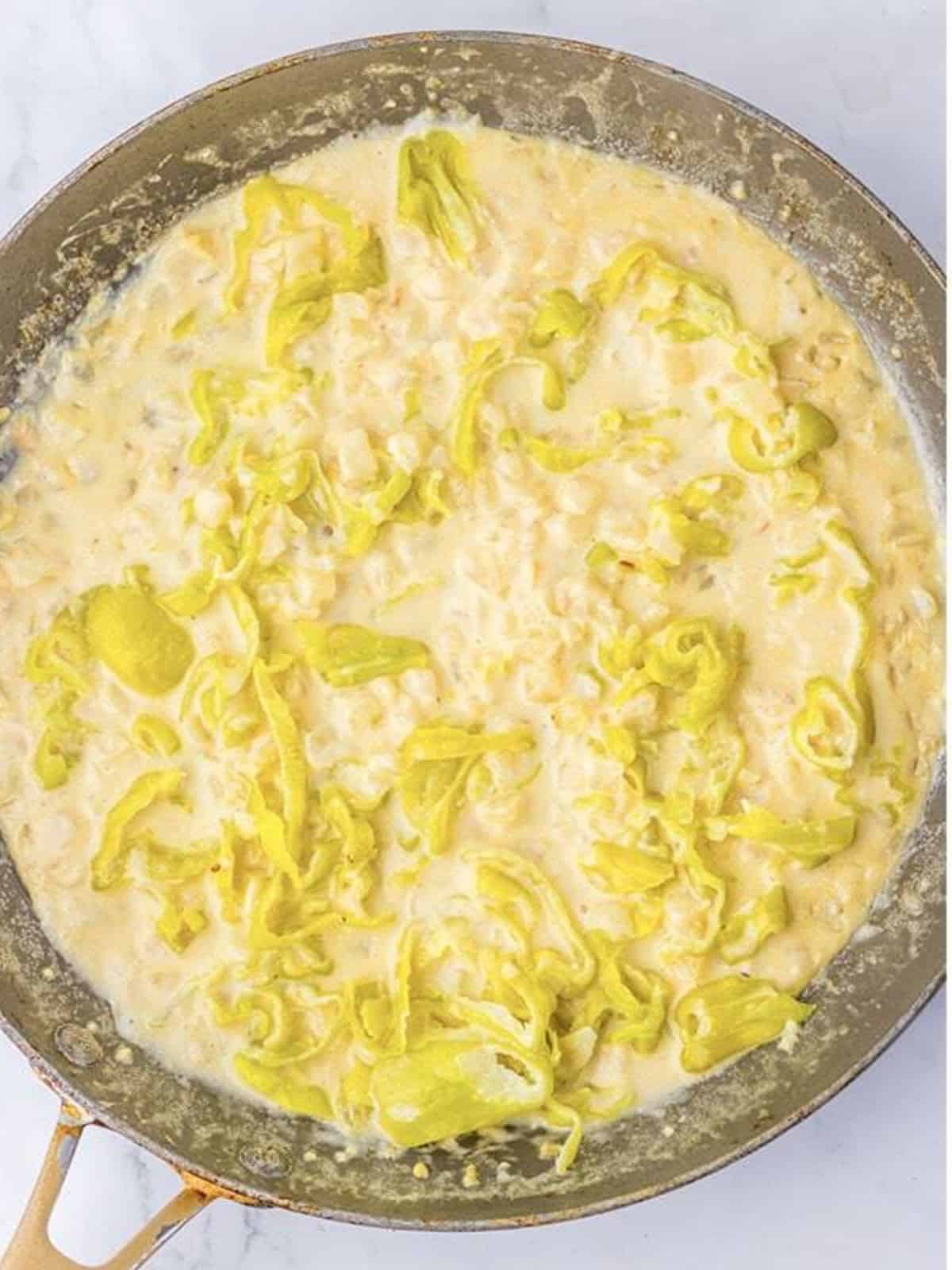 A creamy pepperoncini sauce with Parmesan simmering in a skillet.