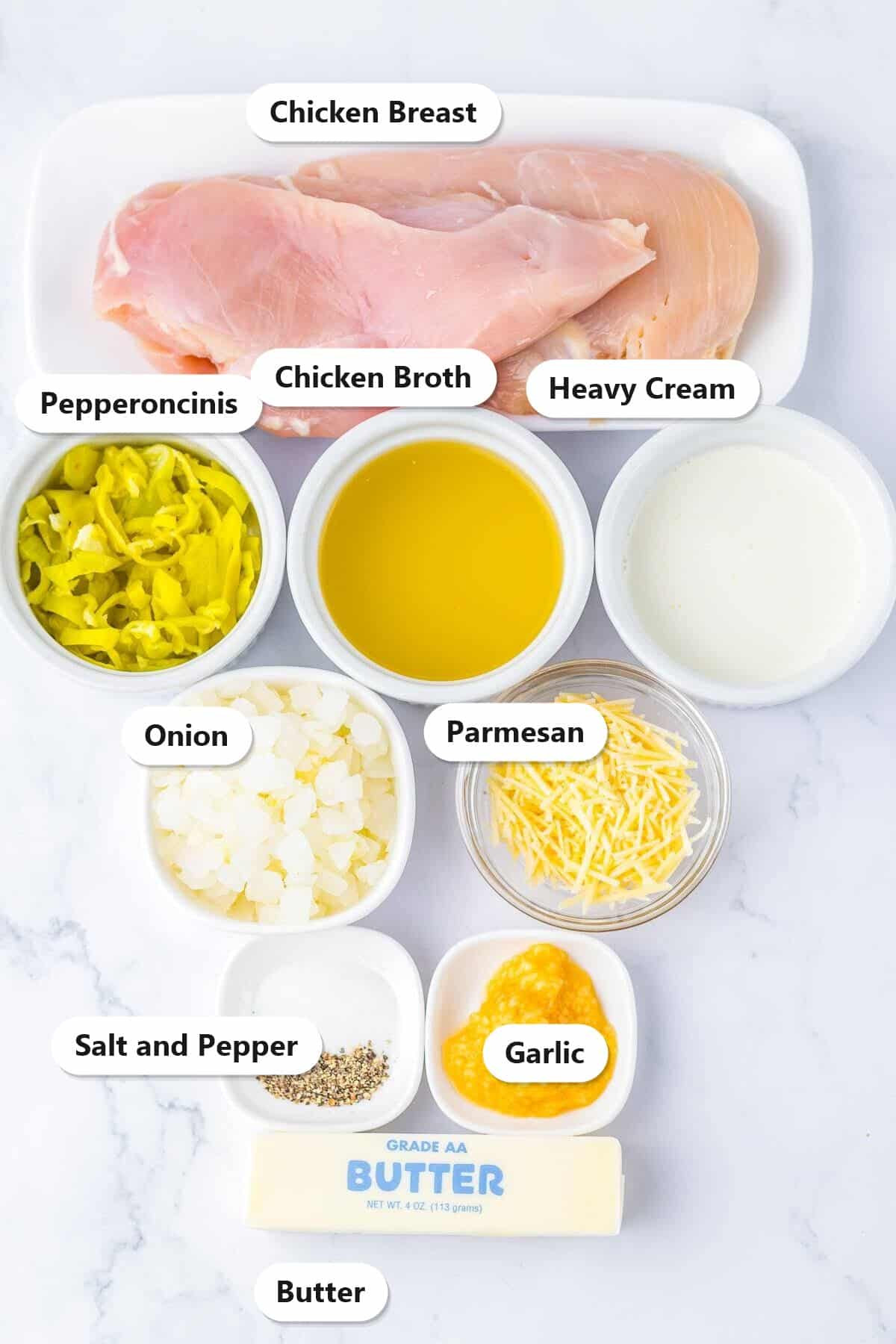 Labeled ingredients for creamy pepperoncini chicken including chicken breast, pepperoncinis, heavy cream, Parmesan, onion, and garlic.