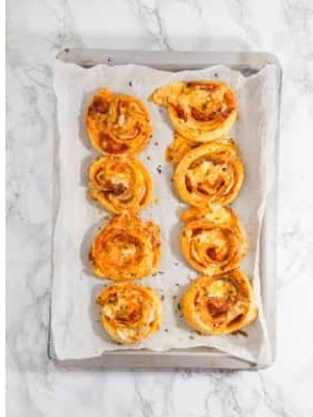 Golden baked pepperoni rolls fresh out of the oven on the tray.