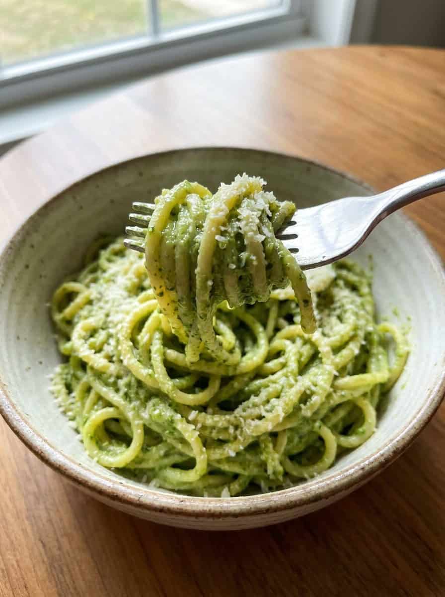 Creamy basil pesto pasta twirled on a fork coated in bright green pesto sauce.