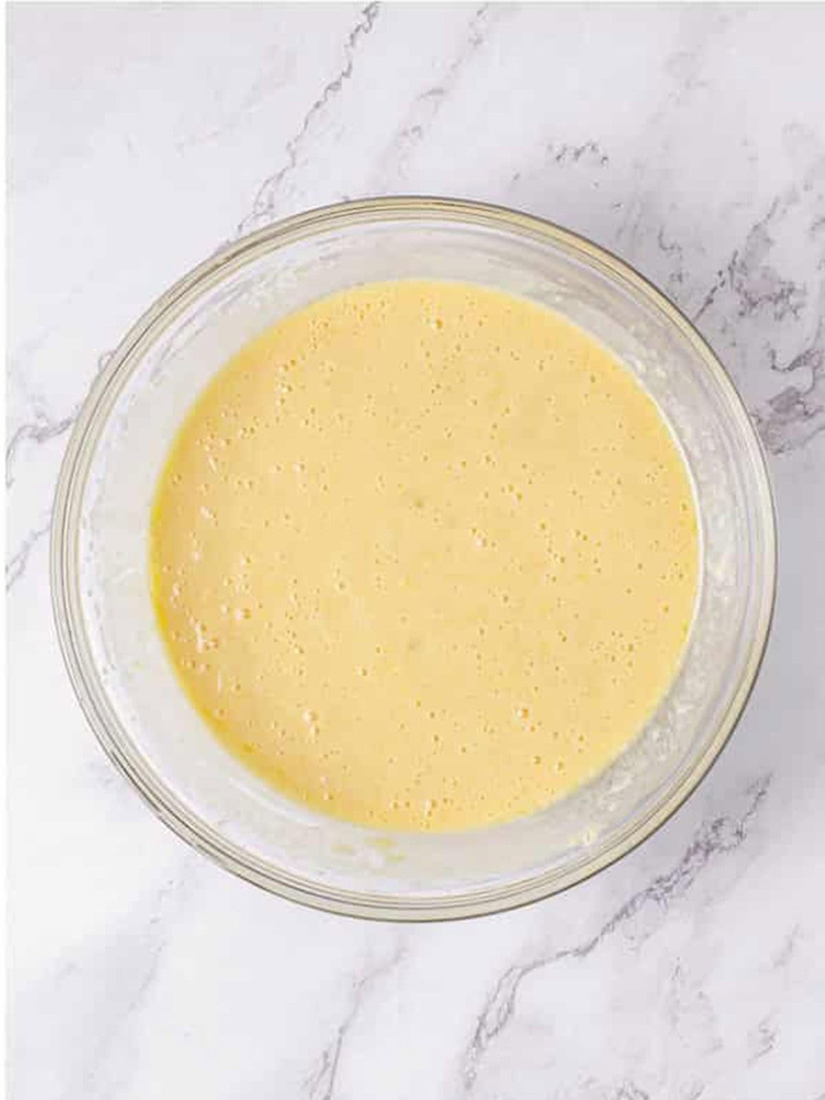 Pina colada cupcake batter mixed with crushed pineapple in a glass bowl.