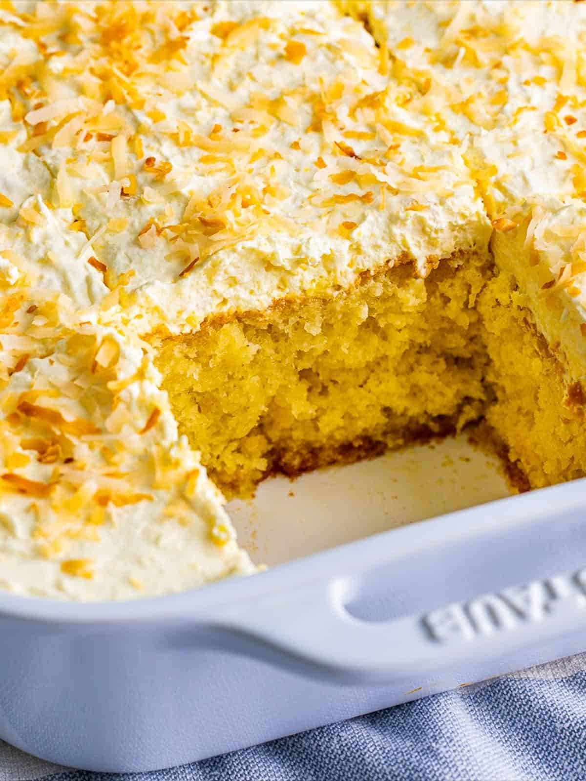 Sliced Pina Colada Cake topped with toasted coconut.
