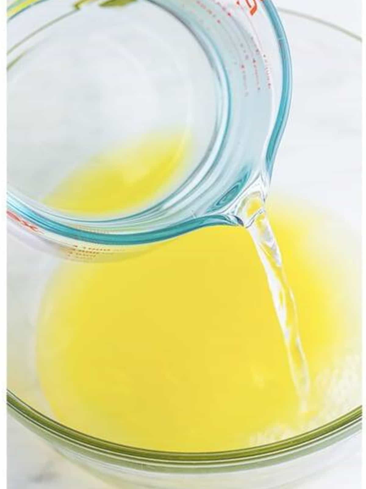 Lemon juice and water poured into a large bowl for pineapple coconut lemonade.