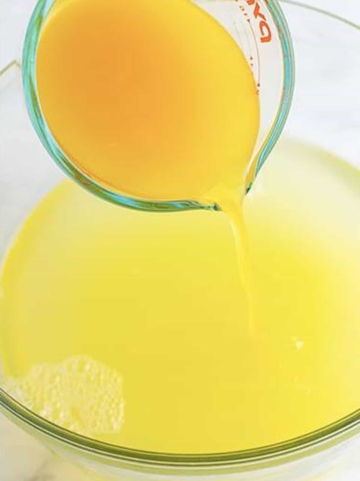 Pineapple juice poured into the lemonade bowl for pineapple coconut lemonade.