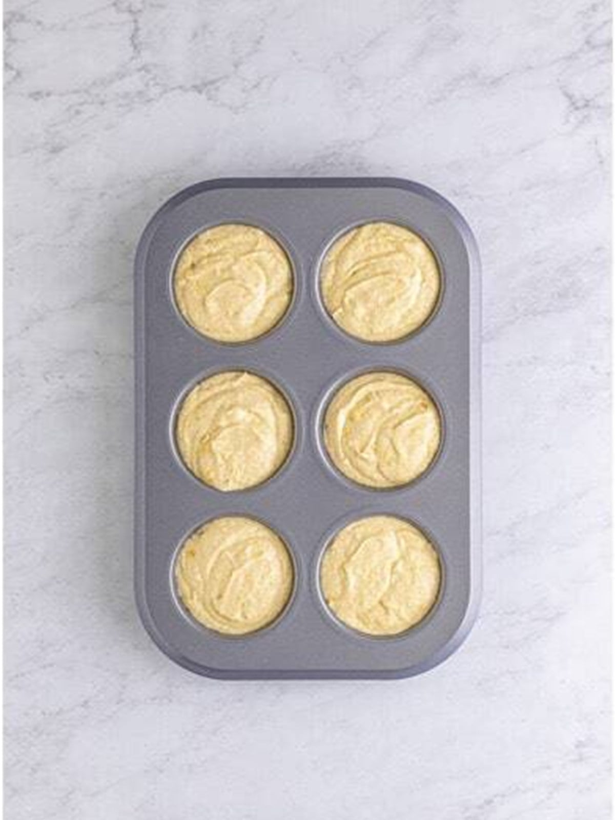 Dividing the cupcake batter into the prepared muffin tin.