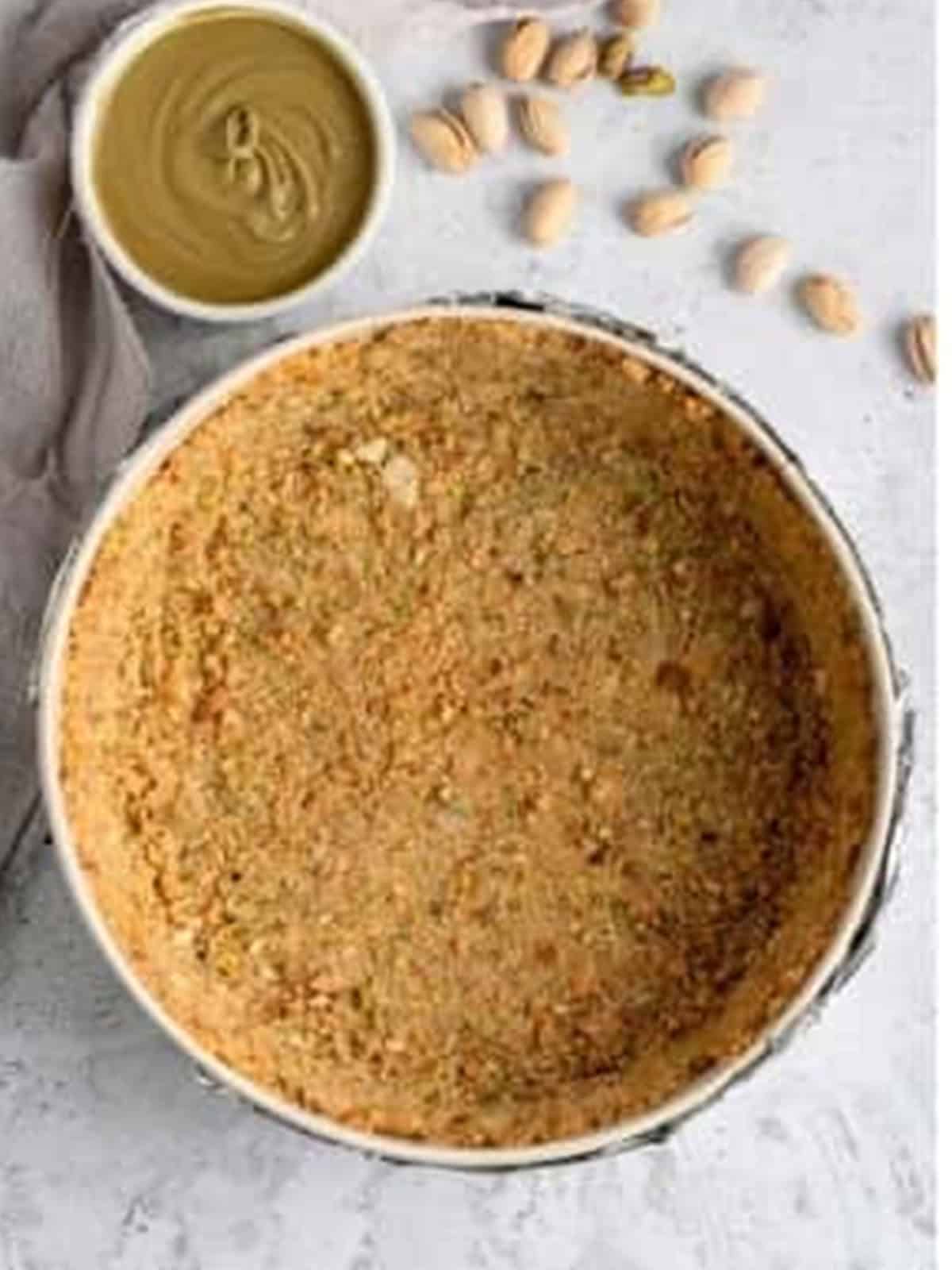 Pressed and baked graham pistachio crust in a springform pan.