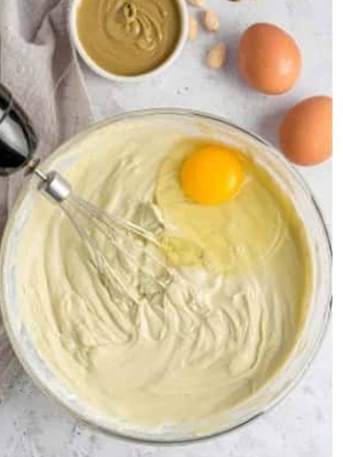 Adding eggs to the pistachio cheesecake filling.