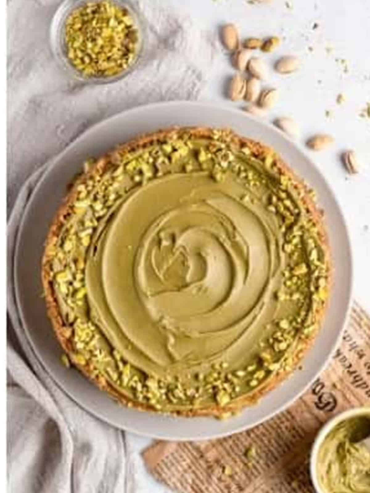 Finished pistachio cheesecake topped with pistachio spread and chopped pistachios.