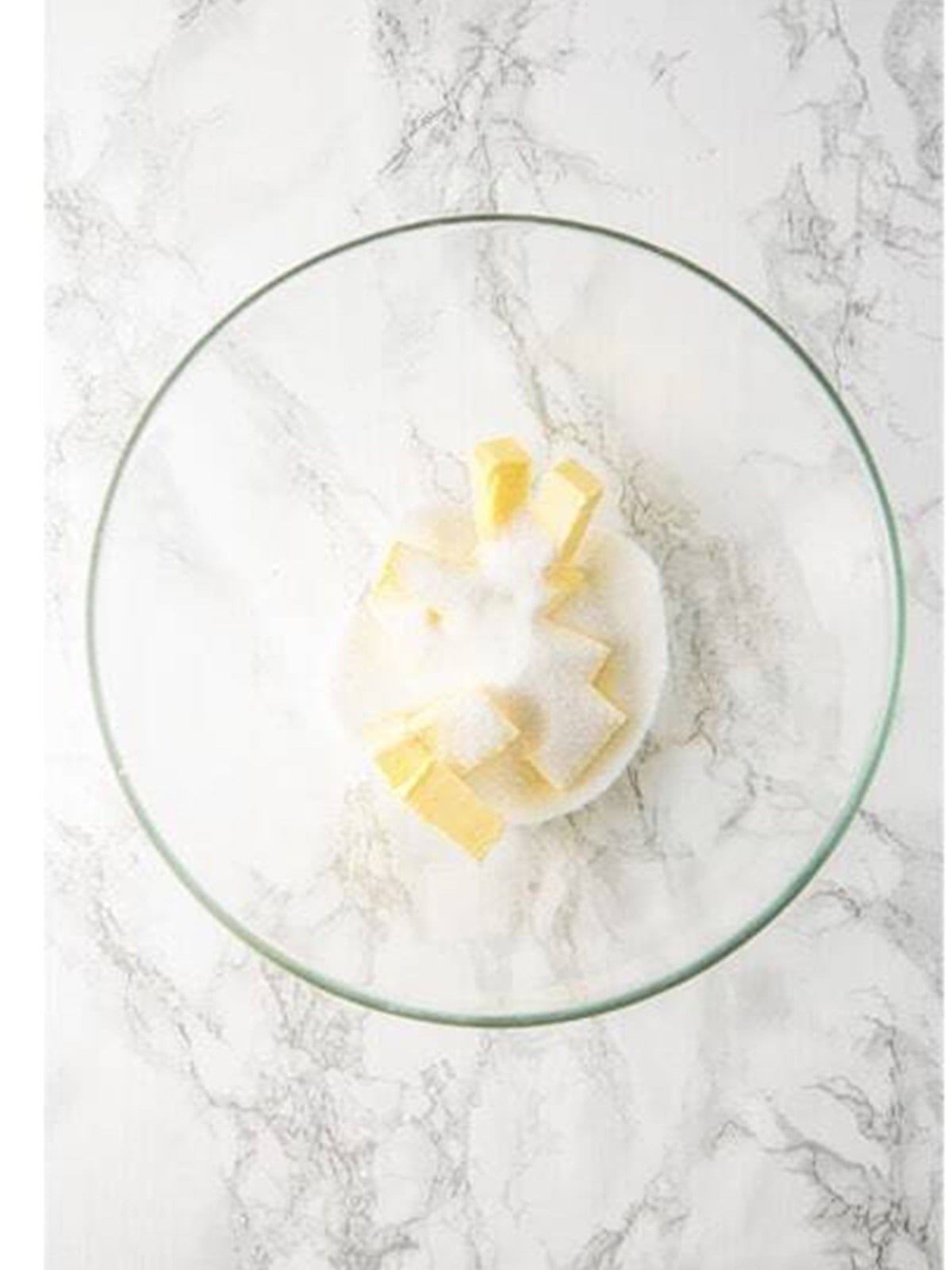 Creaming softened butter and sugar together in a glass bowl.