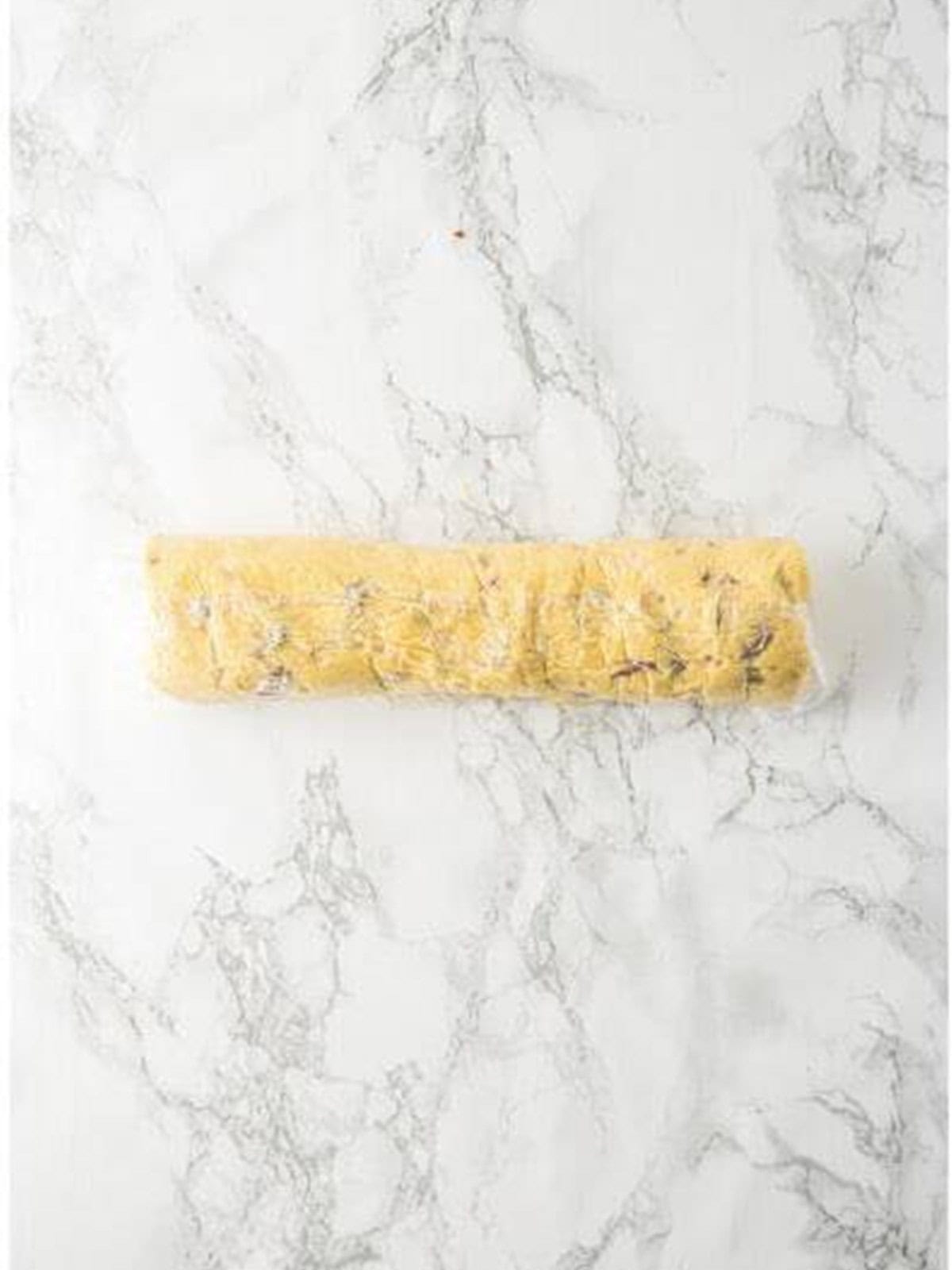 Pistachio cookie dough rolled into a cylinder in plastic wrap.