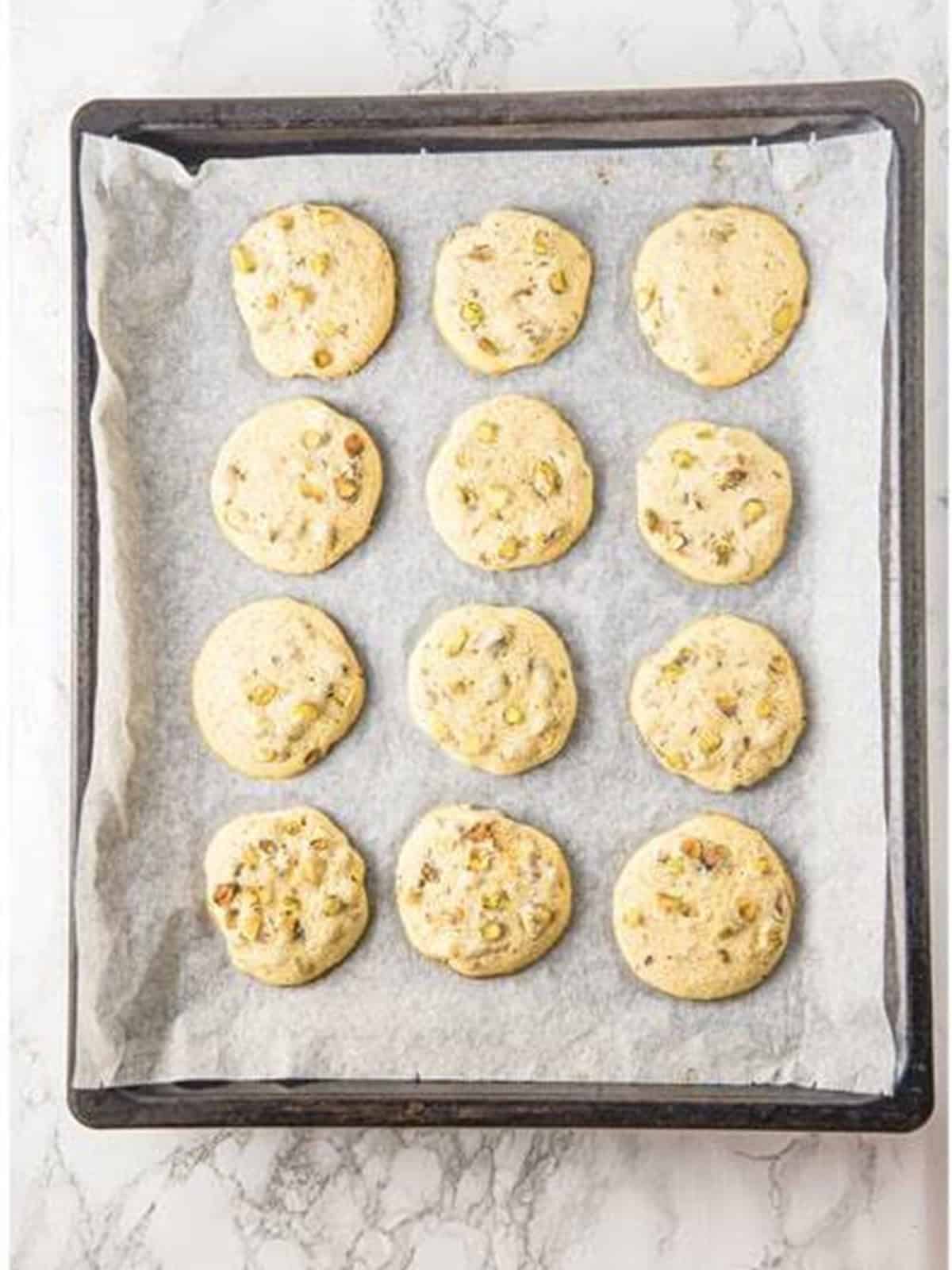 Sliced pistachio cookies baked golden on a parchment-lined tray.