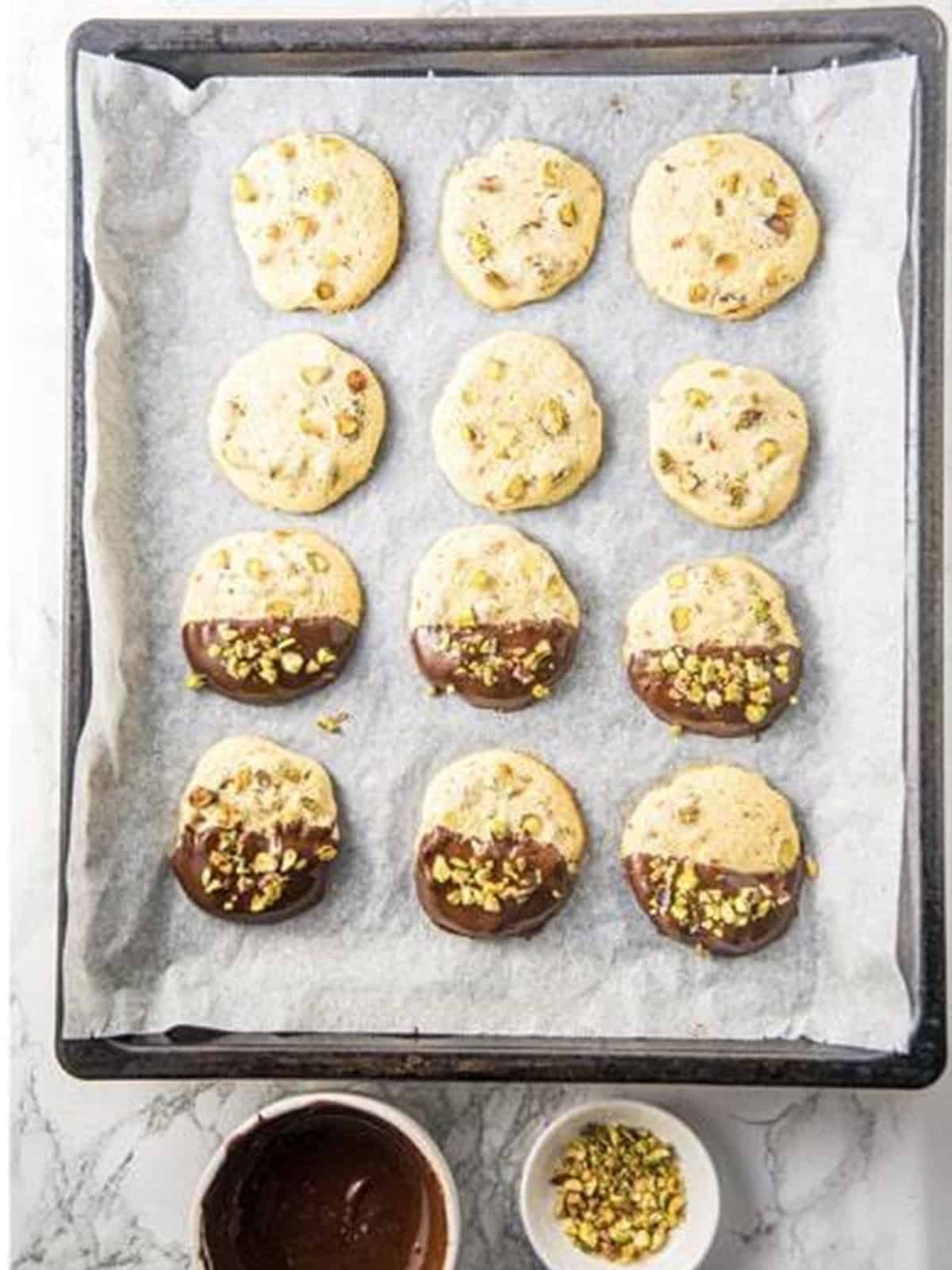 Pistachio cookies dipped in melted dark chocolate and topped with chopped pistachios.