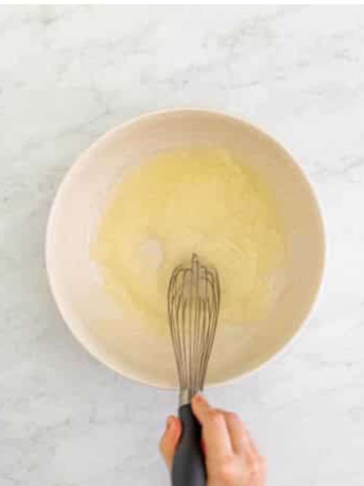 Sugar and oil whisked together in a bowl for pistachio muffins.