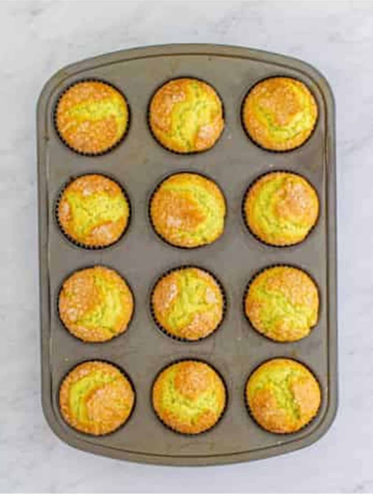 Golden baked pistachio muffins in a muffin tin.