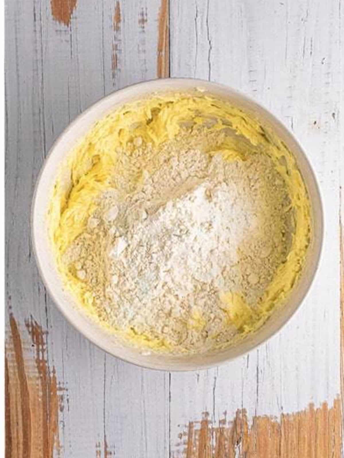 Adding eggs to the creamed butter and sugar for pistachio cookies.