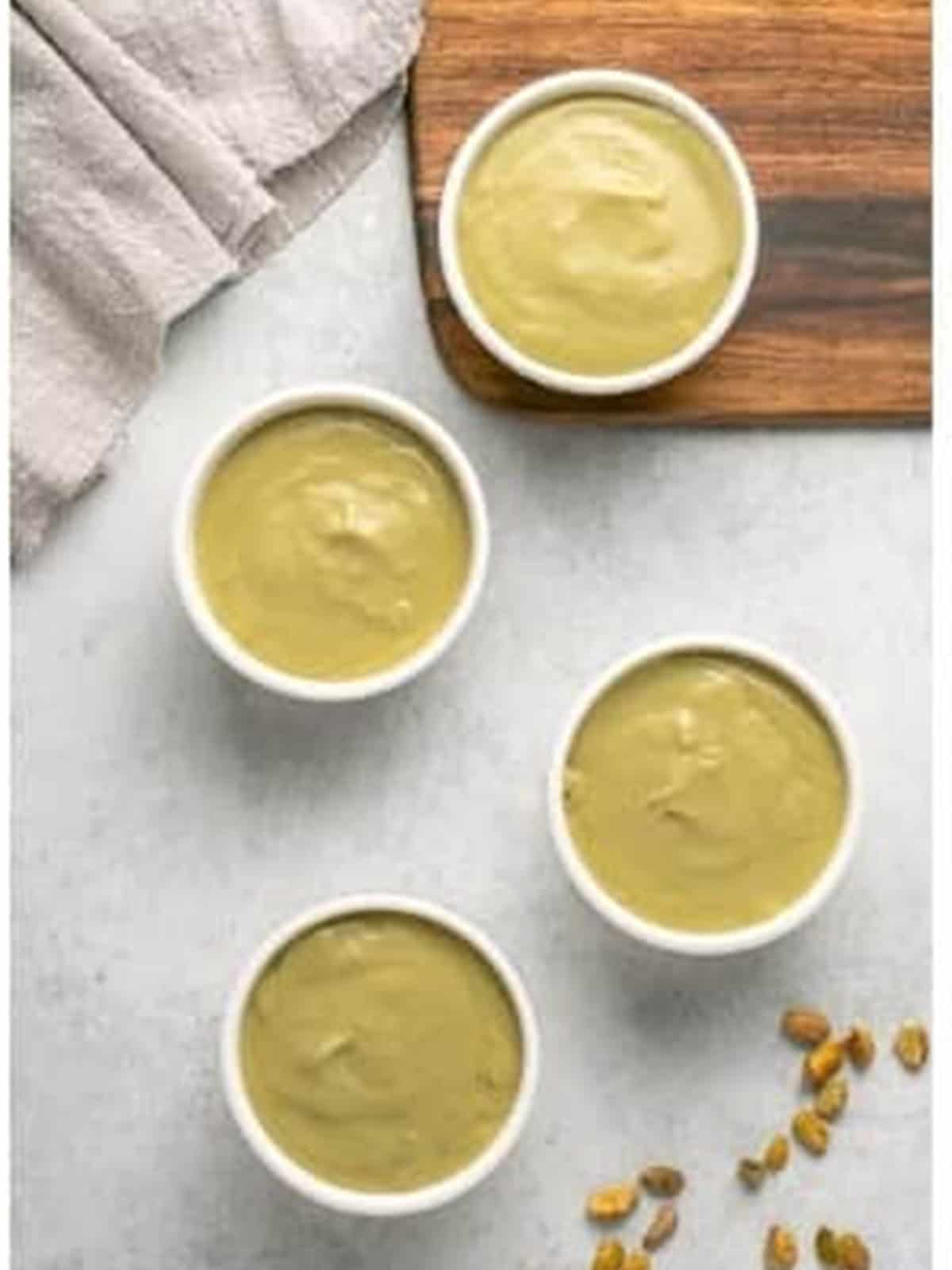 Pistachio pudding recipe poured into four white ramekins.