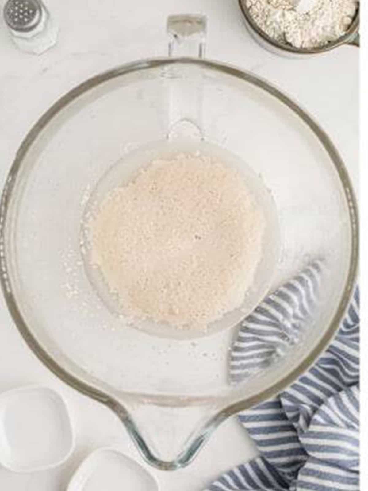 Active dry yeast blooming and turning frothy in warm water for pizza dough.
