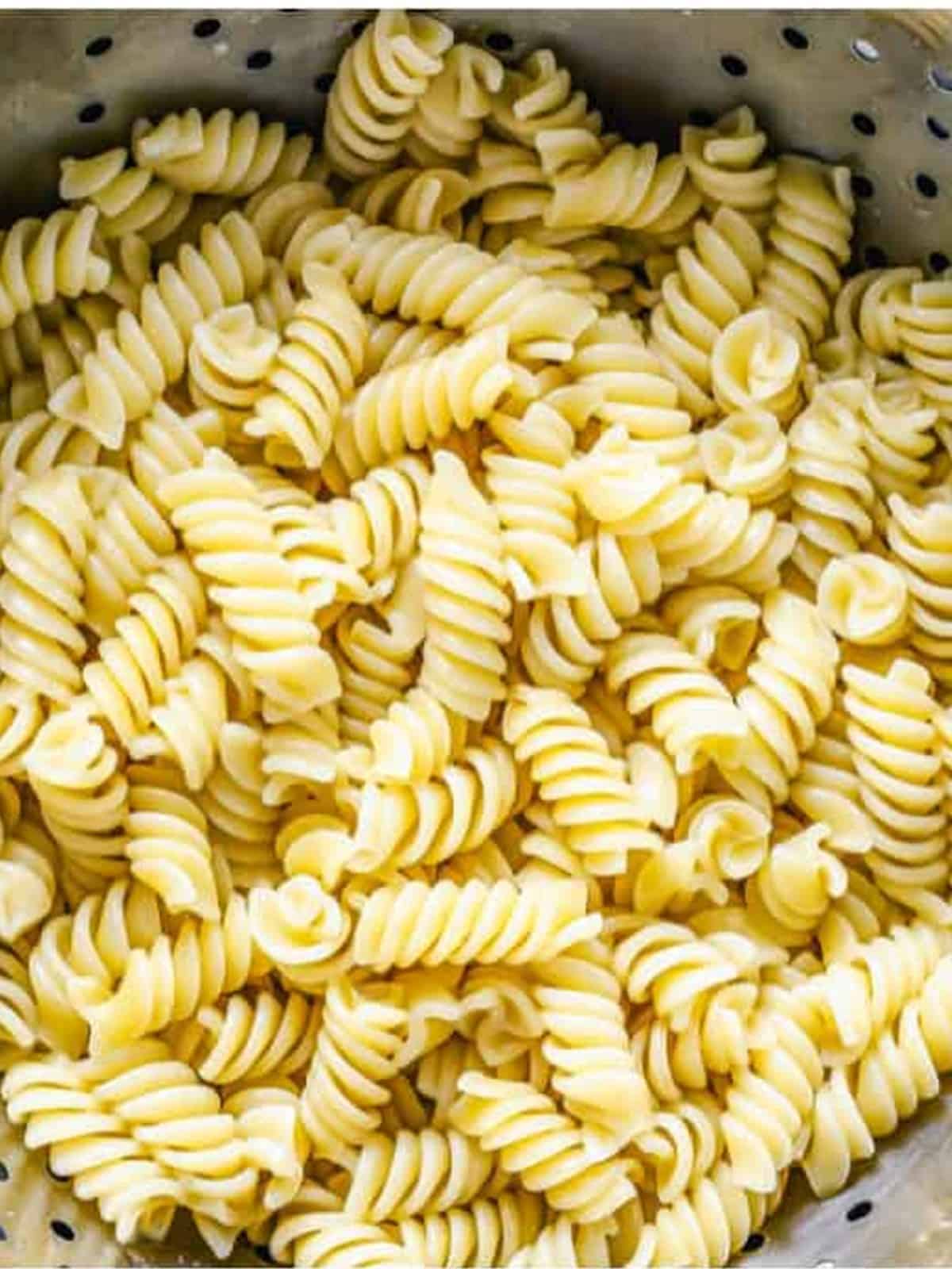 Cooked rotini pasta drained in a colander for pizza pasta casserole.