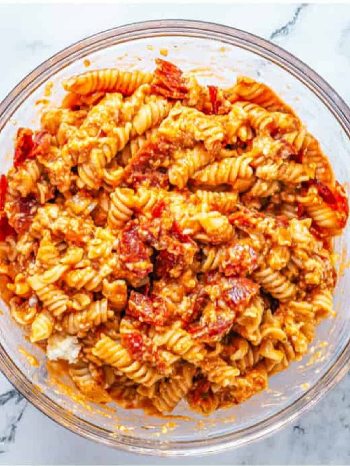 Rotini pasta tossed with spaghetti sauce, mozzarella, and pepperoni in a bowl.