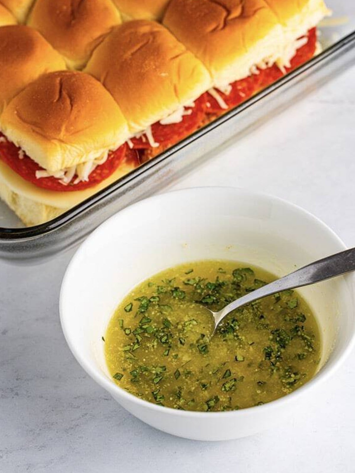 A garlic butter and basil topping brushed over the tops of the pizza slider rolls.