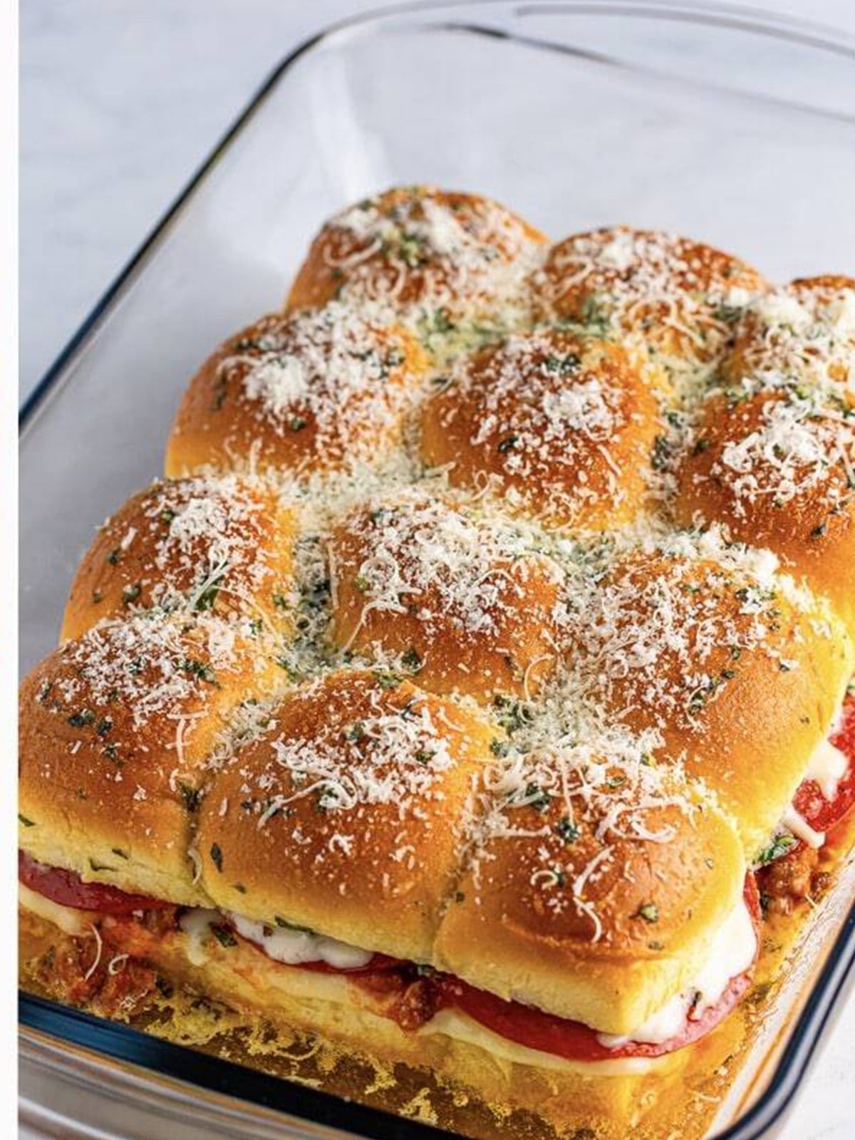 Golden baked pizza sliders topped with parmesan in the baking dish.