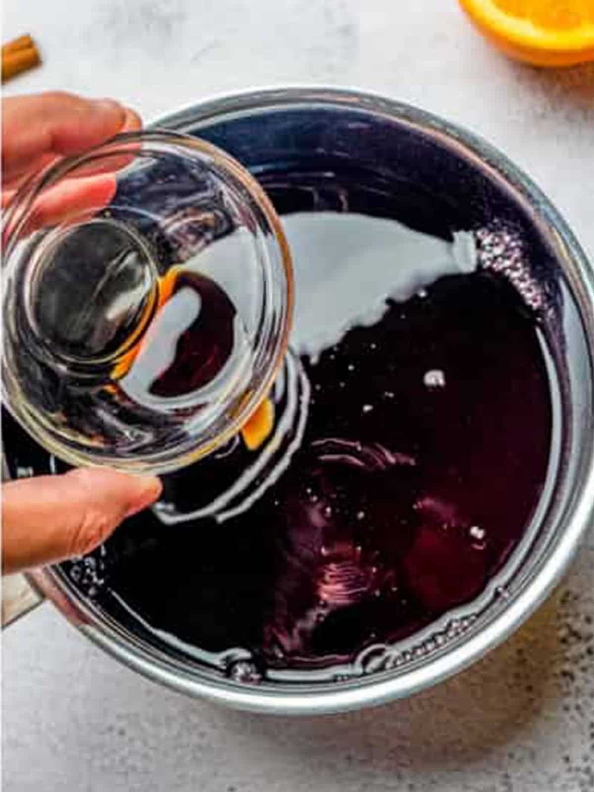 Red wine, sugar, and vanilla added to a pot to make a poaching liquid.