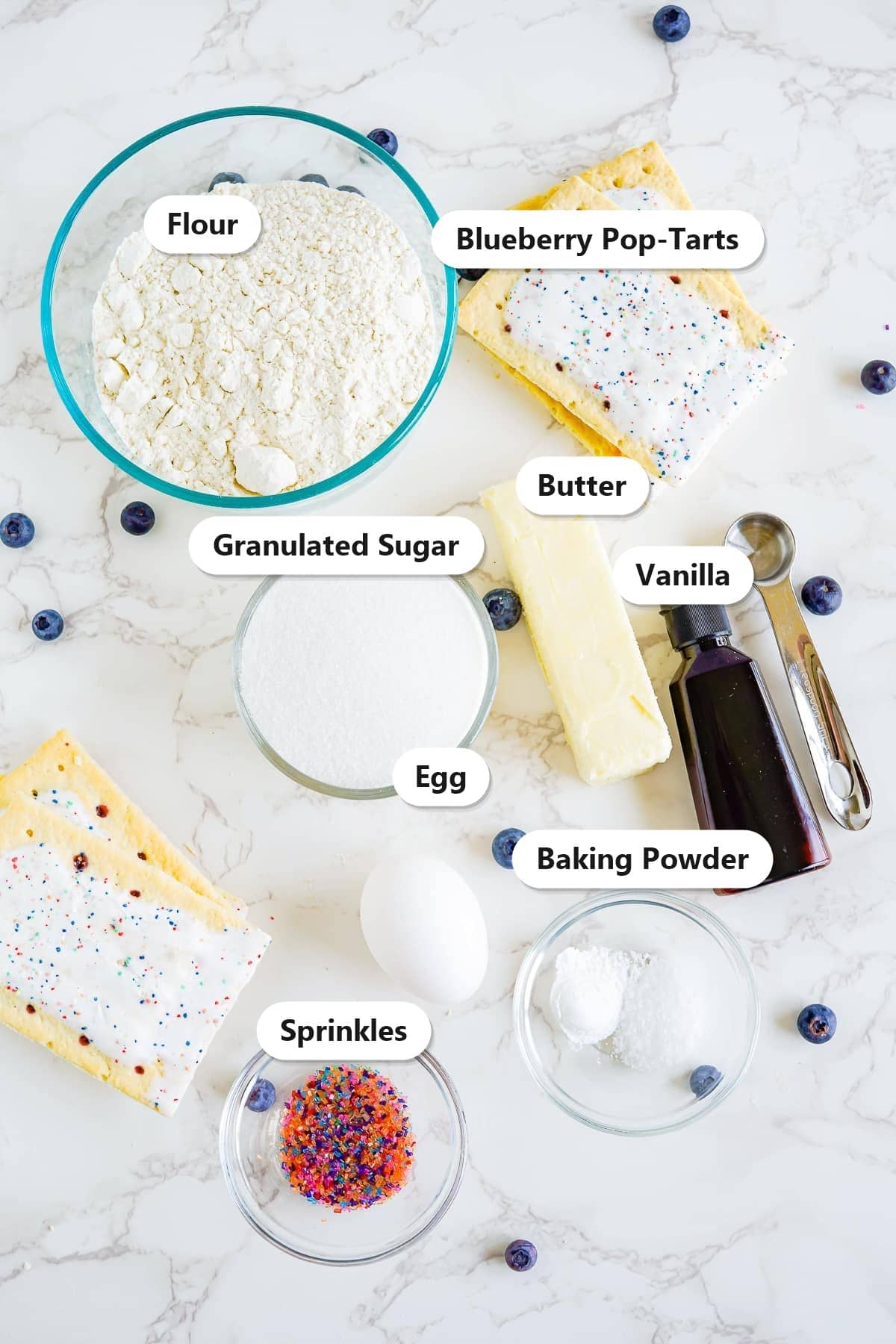 Labeled ingredients for blueberry pop tart sugar cookies including flour, butter, sugar, egg, Pop-Tarts, and sprinkles.