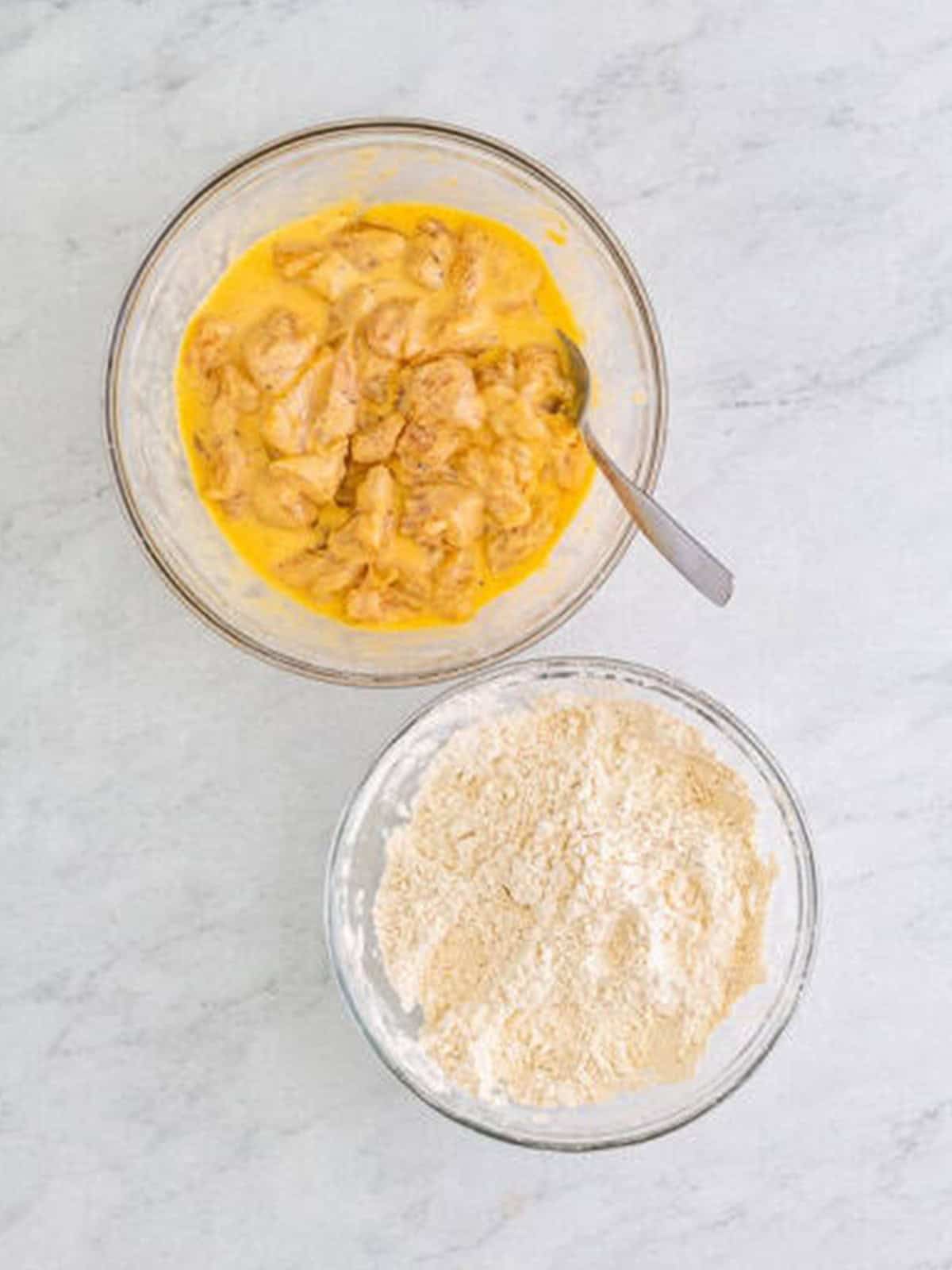 Floured chicken pieces dipped into the egg and buttermilk mixture for popcorn chicken.