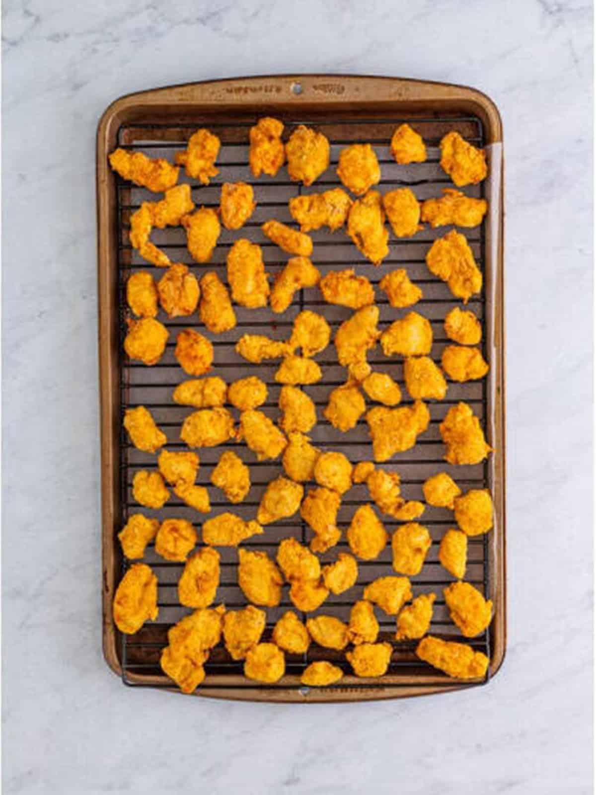 Crispy golden popcorn chicken cooling on a wire rack.