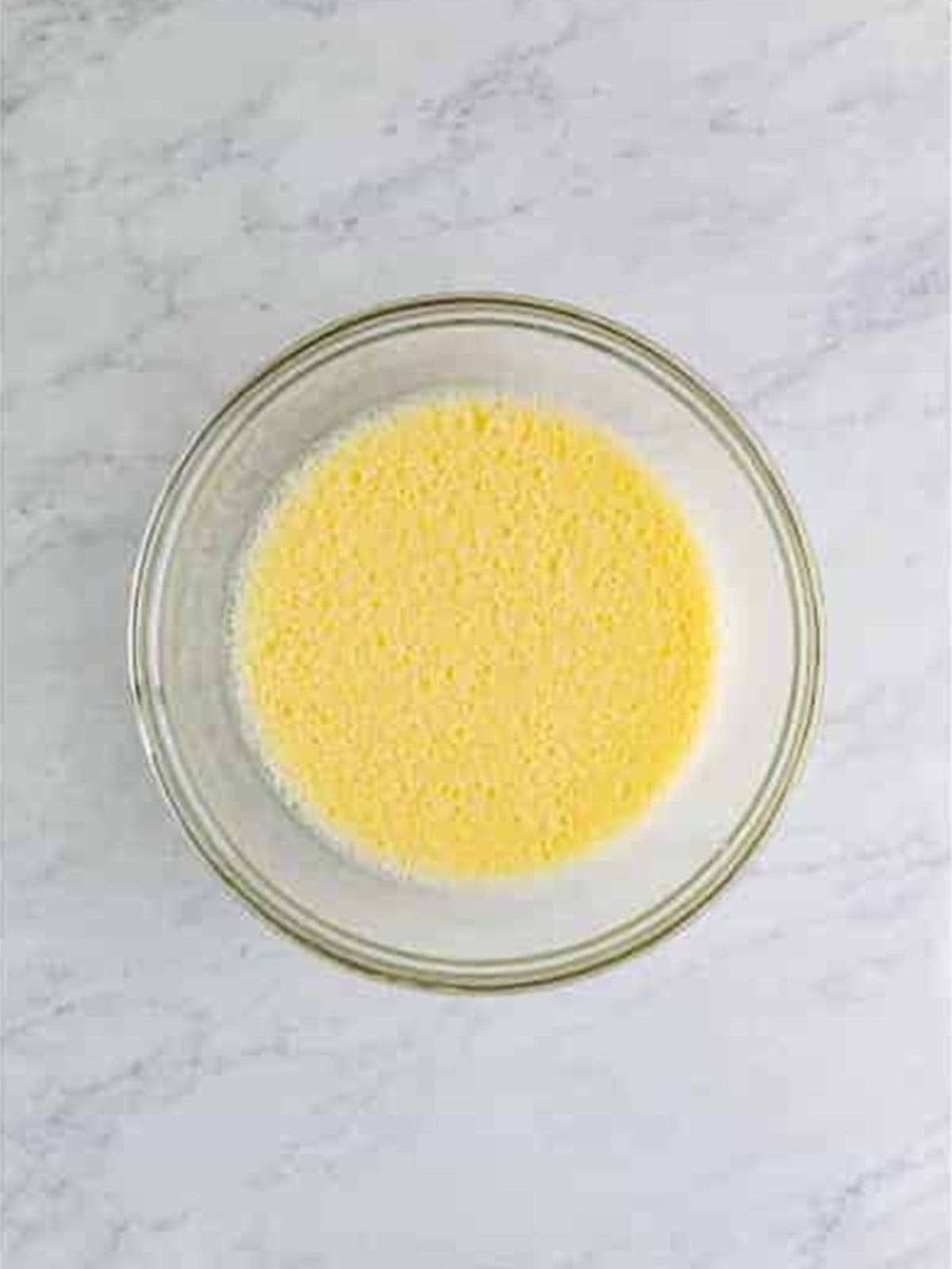 Eggs and milk whisked together until frothy in a glass bowl.