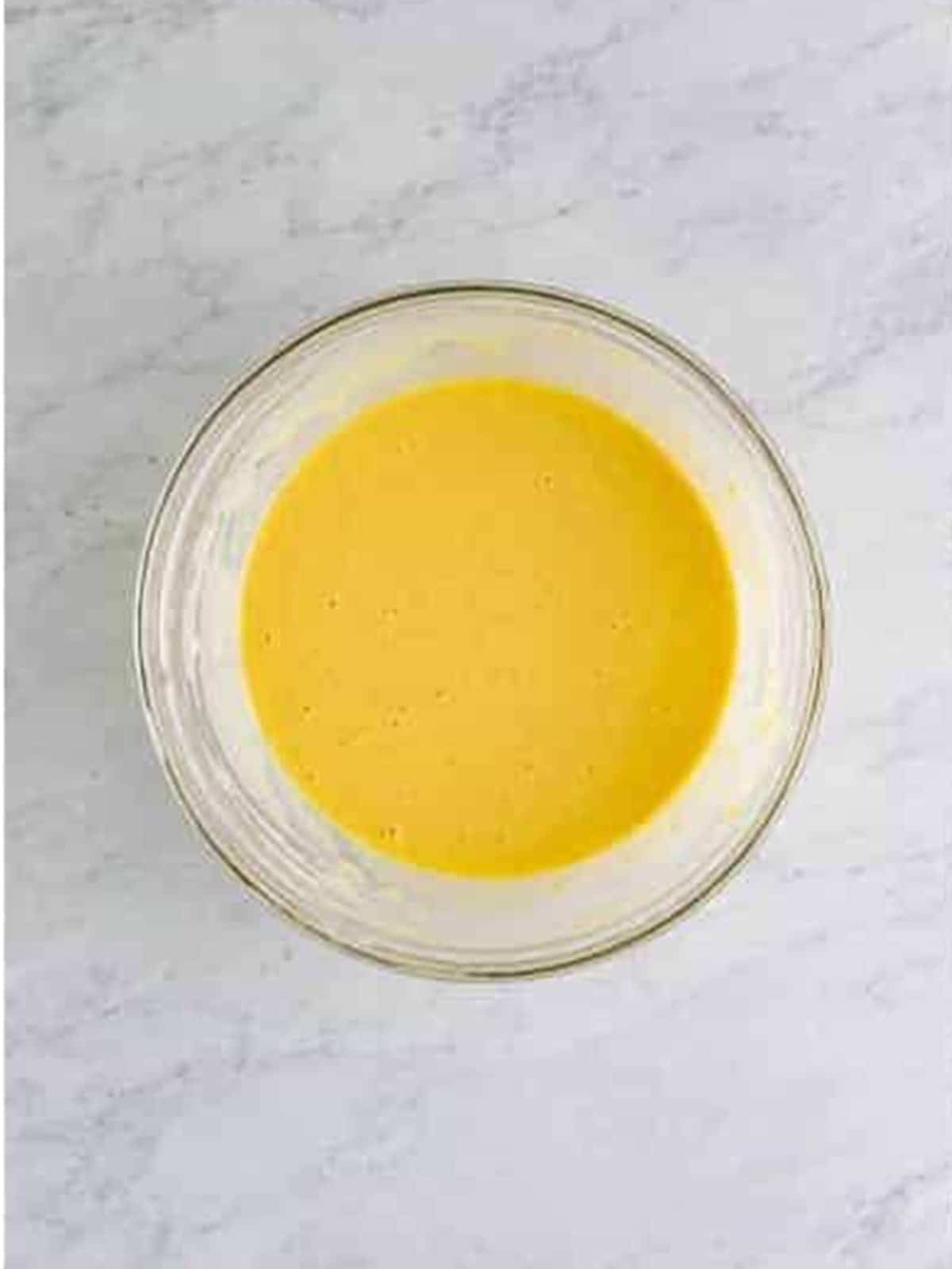 Smooth popover batter whisked in a glass bowl.