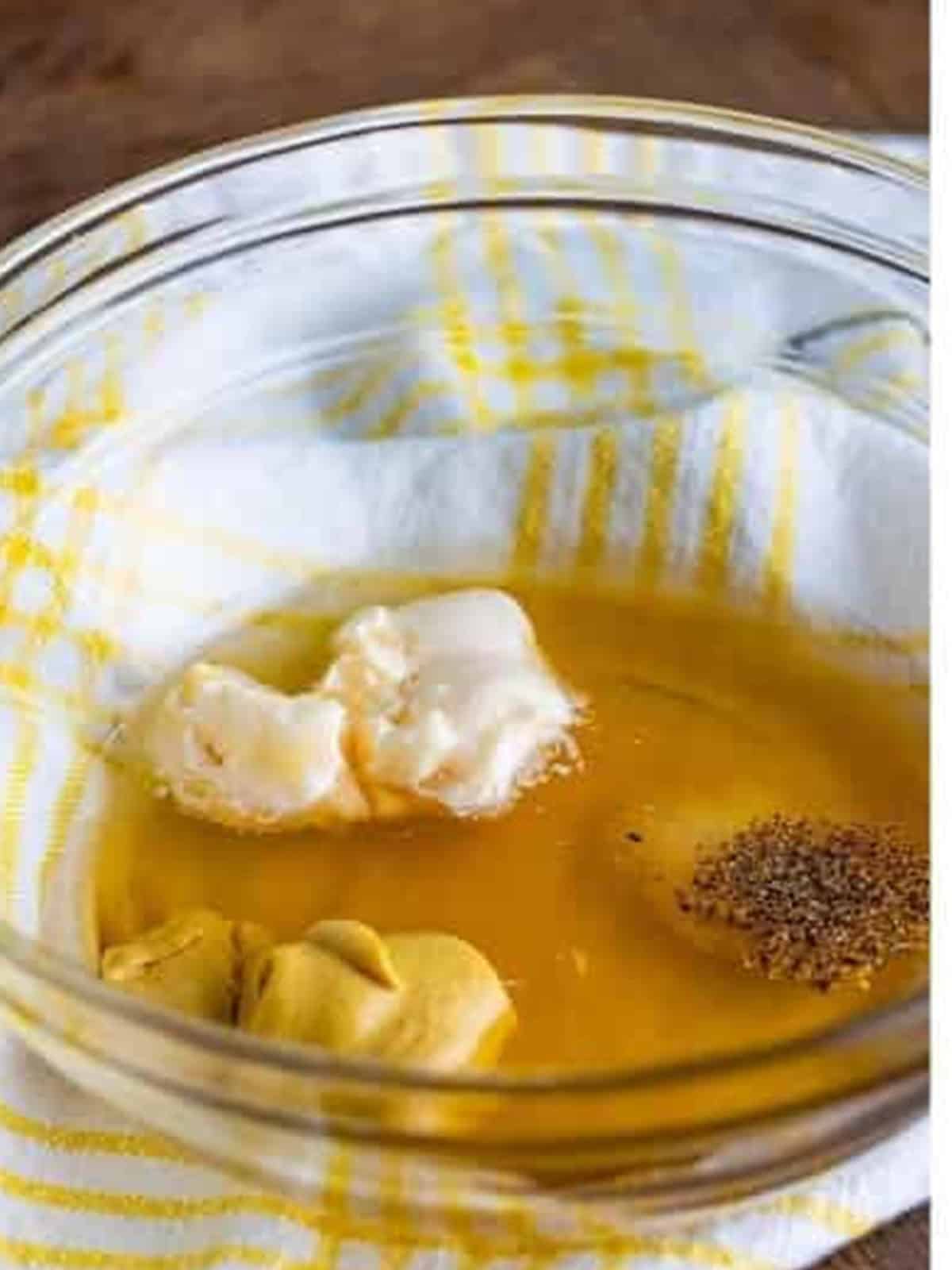 Honey, vinegar, lemon juice, mayonnaise, dijon mustard, salt, and pepper added to a glass bowl.