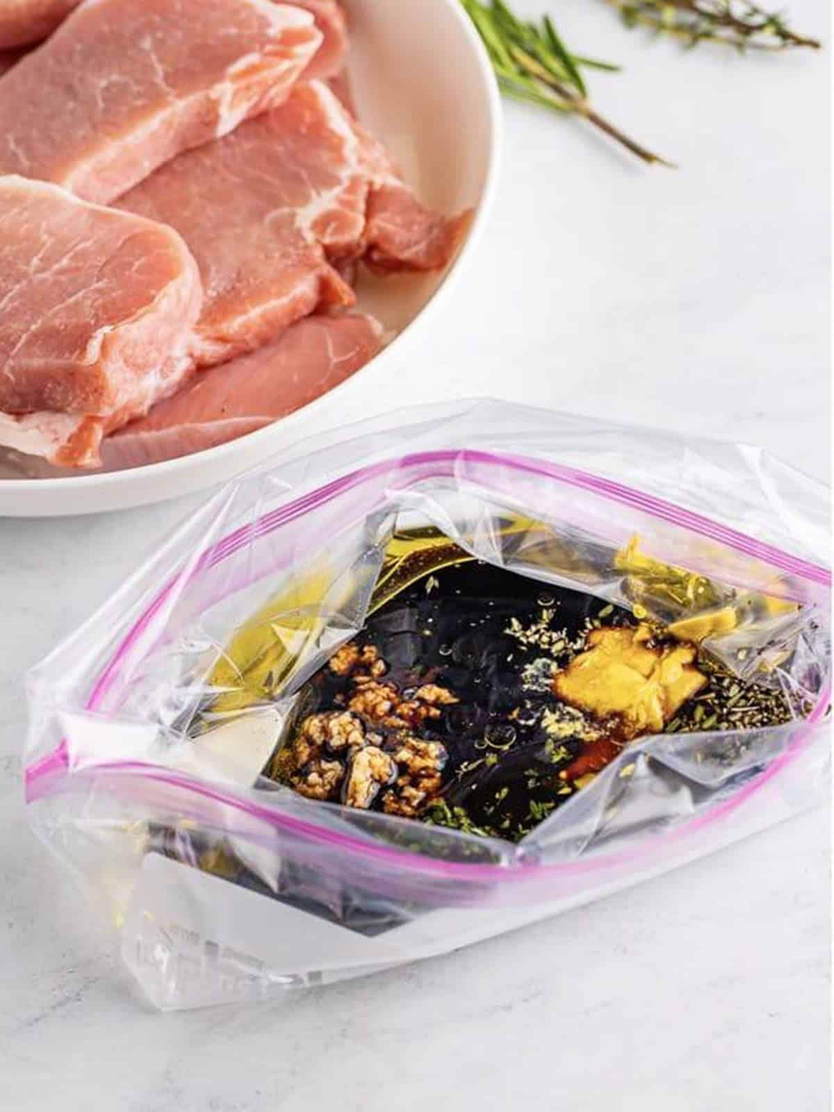 Balsamic vinegar, olive oil, honey, dijon, garlic, and herbs added to a zip-top bag to make pork chop marinade.