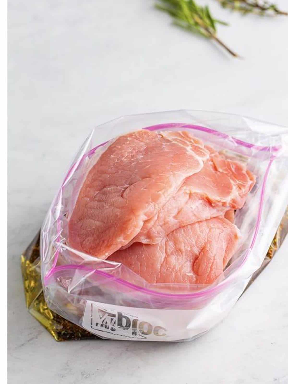 Raw pork chops added to the bag of balsamic marinade.