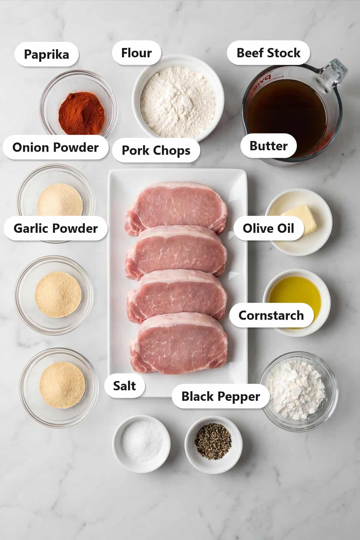 Labeled ingredients to make pork chops with gravy including pork loin chops, flour, paprika, onion powder, garlic powder, beef stock, butter, and cornstarch.