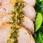 Sliced brown sugar balsamic pork tenderloin drizzled with marinade sauce on fresh greens.