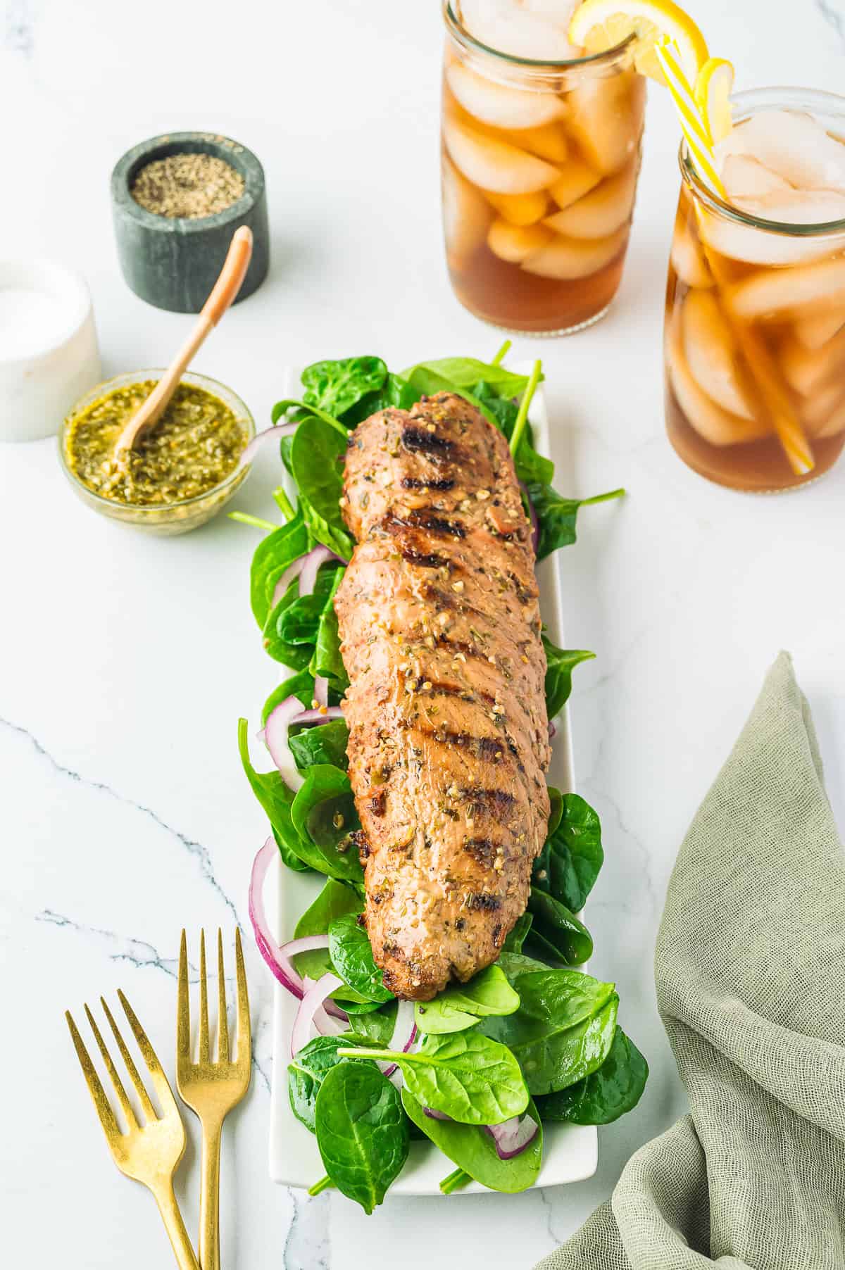Plated grilled pork tenderloin sliced and served with fresh greens.